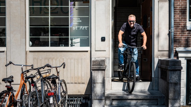 Bert op zijn VanMoof voor de deur Wheelhouse Amsterdam, waar hij kantoor houdt