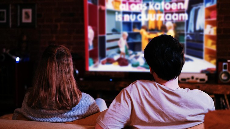 2 personen op een bank, kijkend naar een televisie