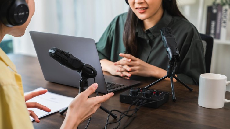 Een foto van twee vrouwen die een podcast opnemen.