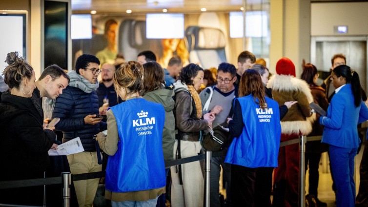 KLM-medewerkers helpen reizigers op luchthaven Schiphol bij sneeuwproblemen