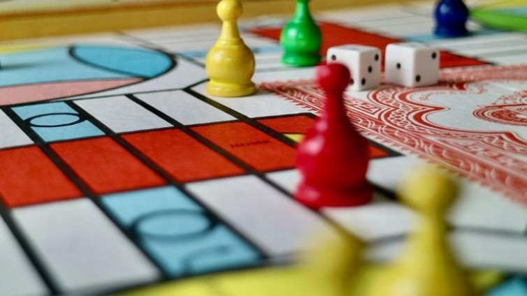 Close-up van een kleurrijk bordspel met pionnen en dobbelstenen.