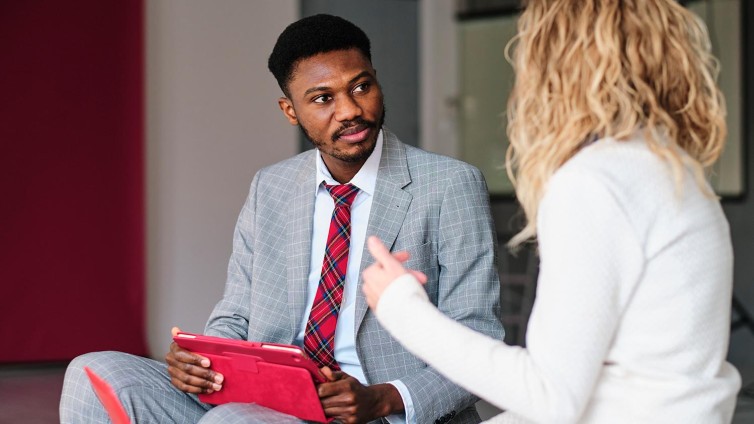 Vrouw wordt door man met rode iPad geïnterviewd.